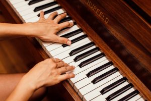 Musicians hands playing wooden piano keys in a high contrast image, capturing musical expression.