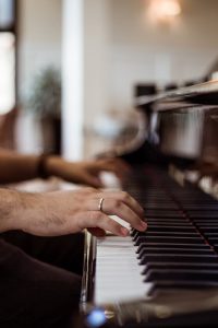 A musicians hands elegantly play a grand piano, showcasing musical expertise and passion.
